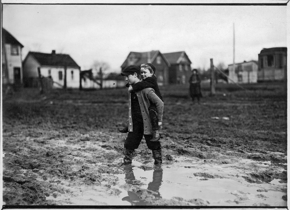 One child piggy-backs another across a muddy road, Earlscourt. - [between 1908 and 1920]