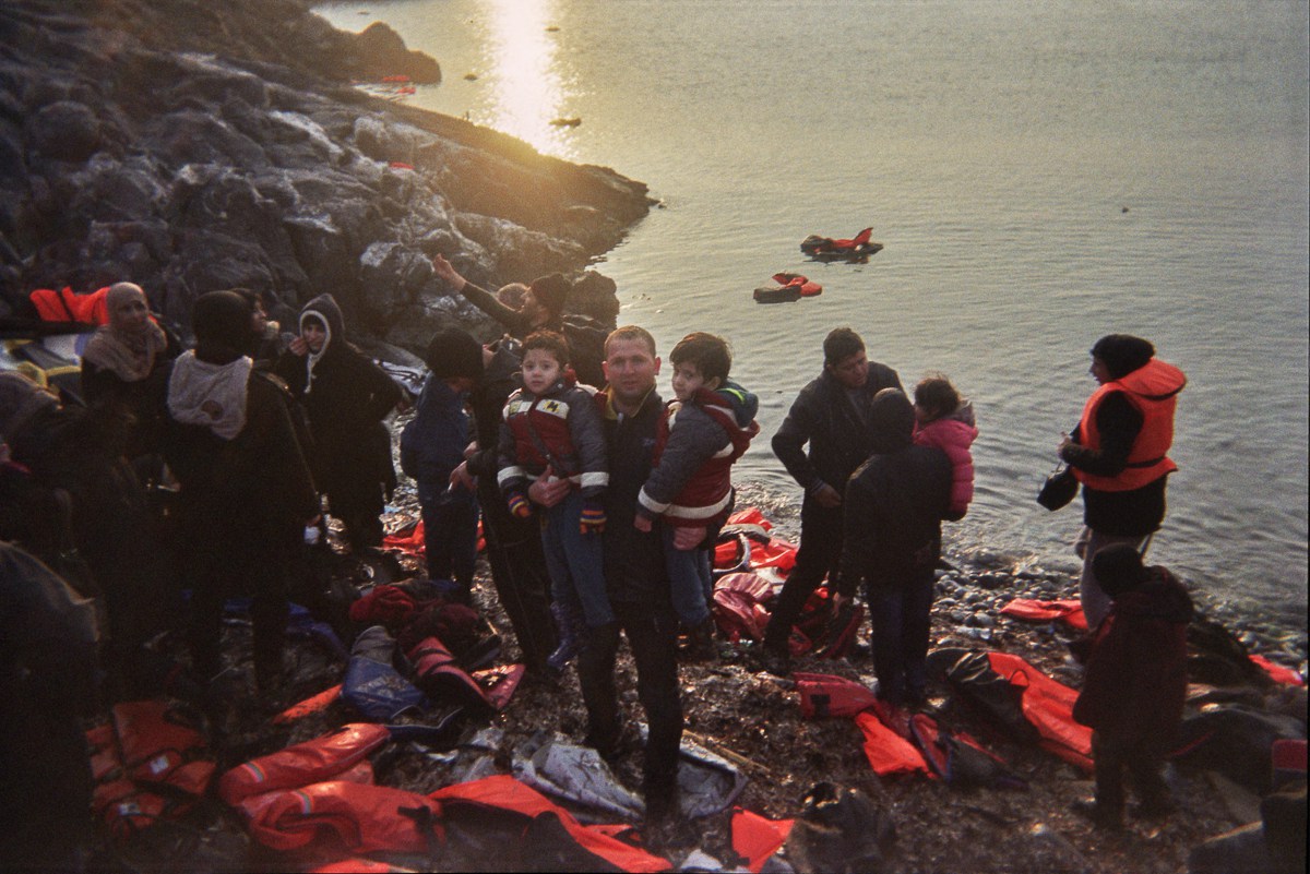 Hamza holds up two boys after all refugees left the dinghy.