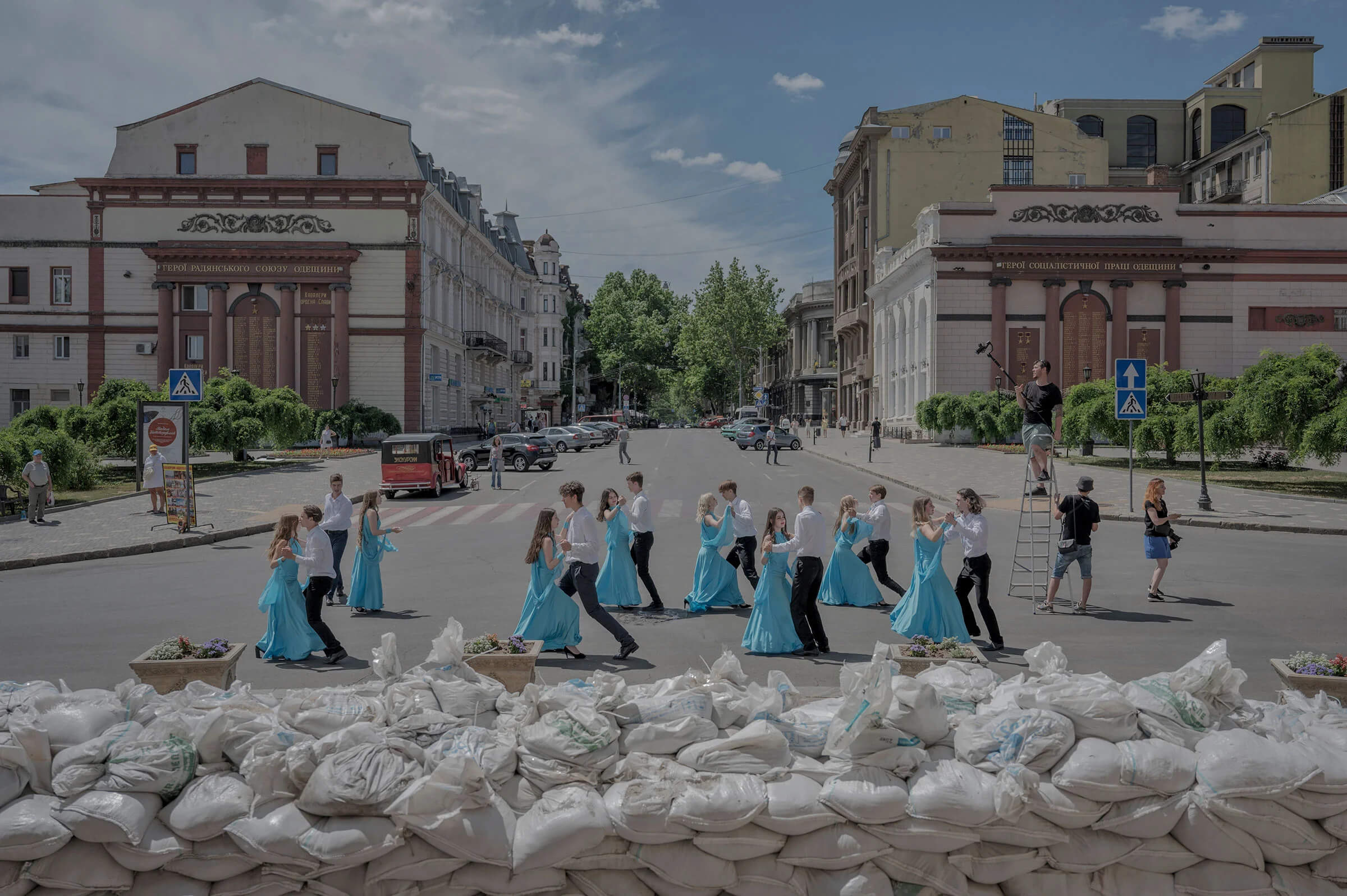 Випускники 11 класу танцюють біля мішків з піском, які захищають фасад Оперного театру, Одеса, 15 червня. Летіція Ванкон для The New York Times 