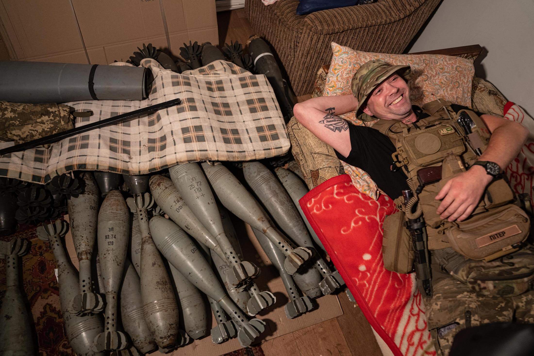 Український військовослужбовець з позивним Пітер відпочиває на мінометних снарядах на передовій. Харківська область, 22 липня 2022 року.