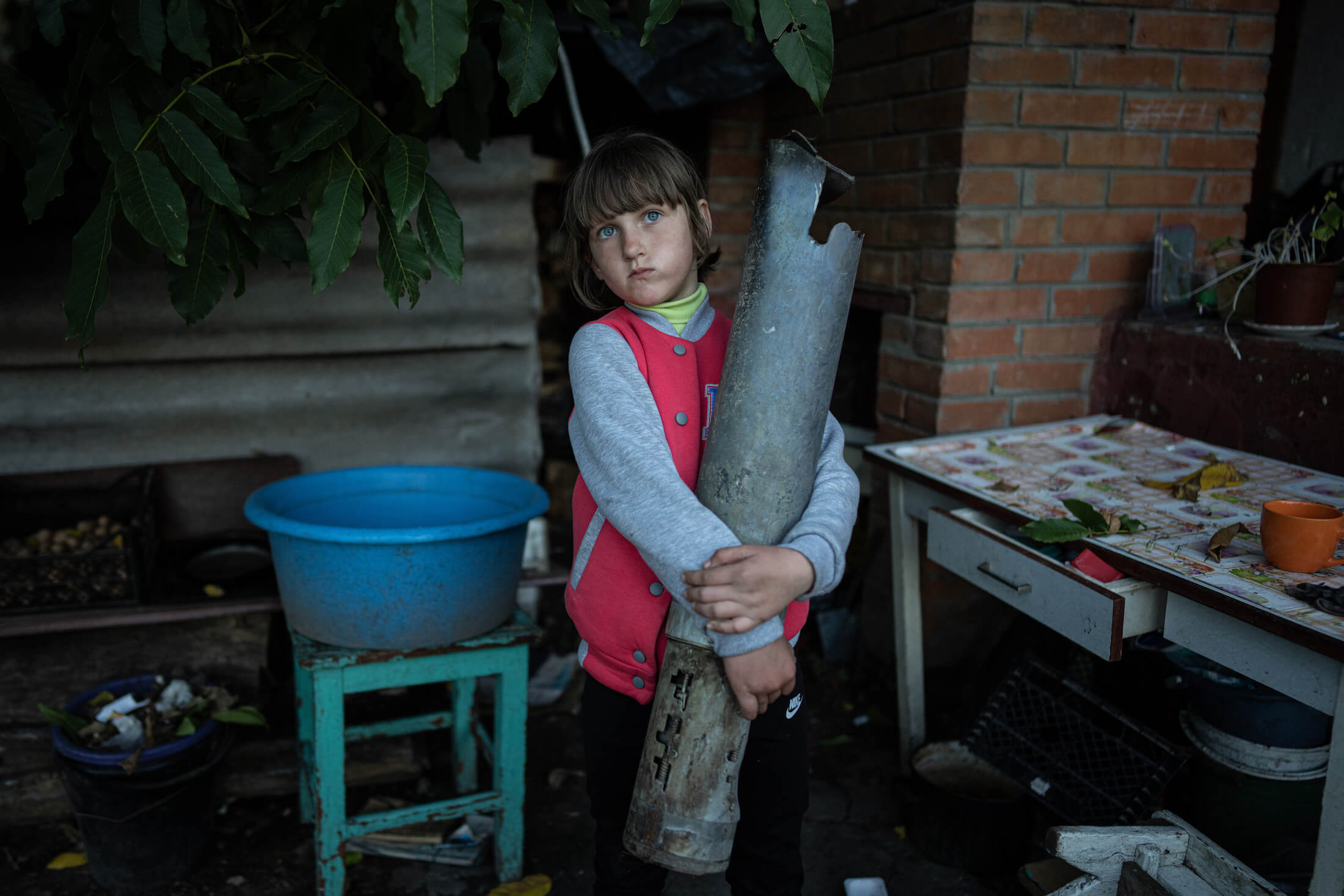 7-річна Вероніка Ткаченко тримає уламок ракети «Град», яка влучила в будинок її родини. Ізюм, 25 вересня 2022 року.